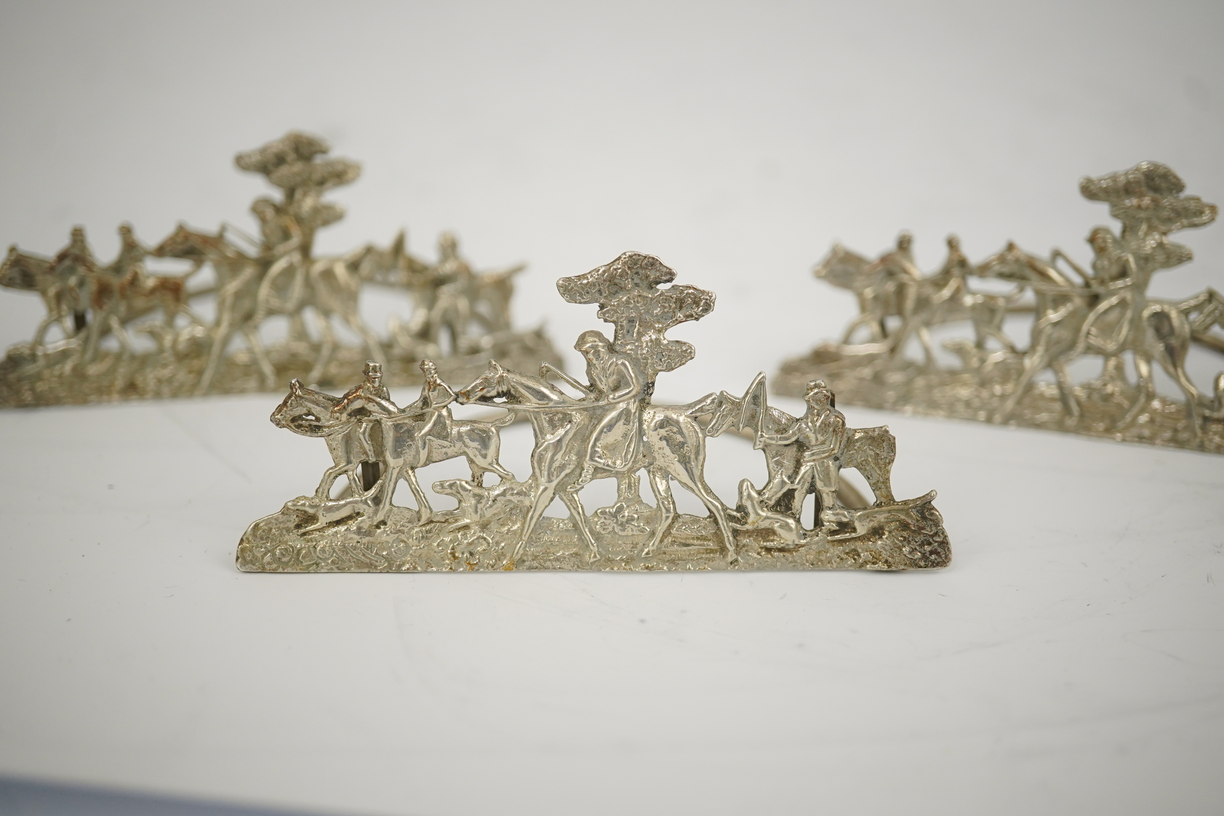 A set of four Edwardian pierced silver 'hunting scene' menu holders, by Stuart Clifford